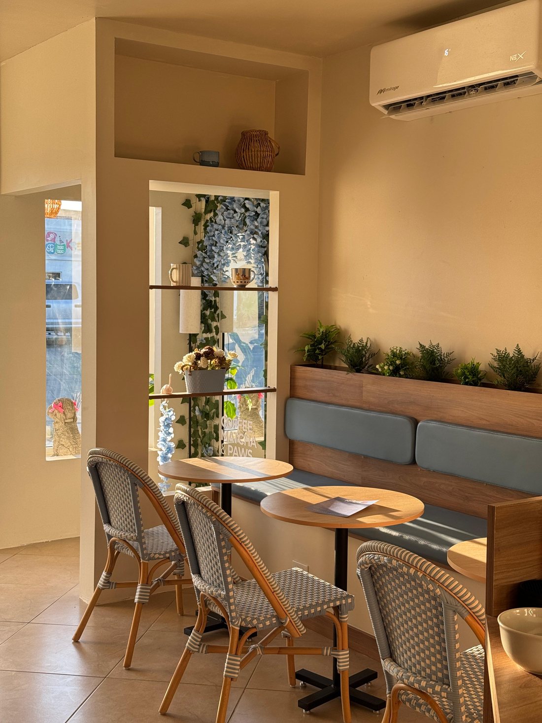 Interior de Nairo Café: sillón azul, mesas redondas y sillas tejidas